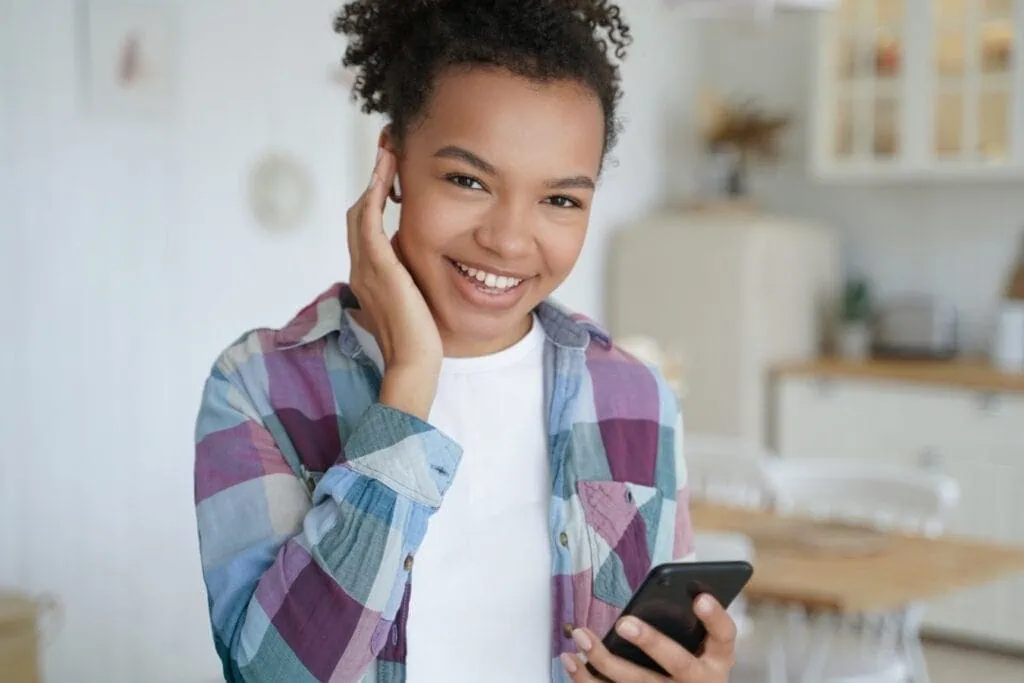 Teen girl smiling and using phone
